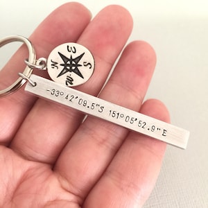 May include: Silver keyring with a compass charm and a bar engraved with the coordinates -33° 42' 09.5" S 151° 05' 52.9" E.