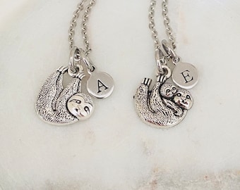 May include: Two silver necklaces with sloth charms. One sloth charm is holding a baby sloth. The necklaces have initial charms with the letters A and E.