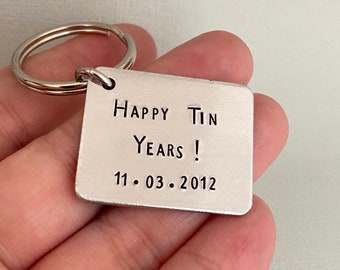 May include: Silver keychain with a rectangular tag that says "Happy Tin Years! 11.03.2012".