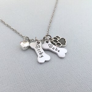 May include: Silver necklace with two bone charms engraved with the names "Becky" and "Babu" and a paw print charm.