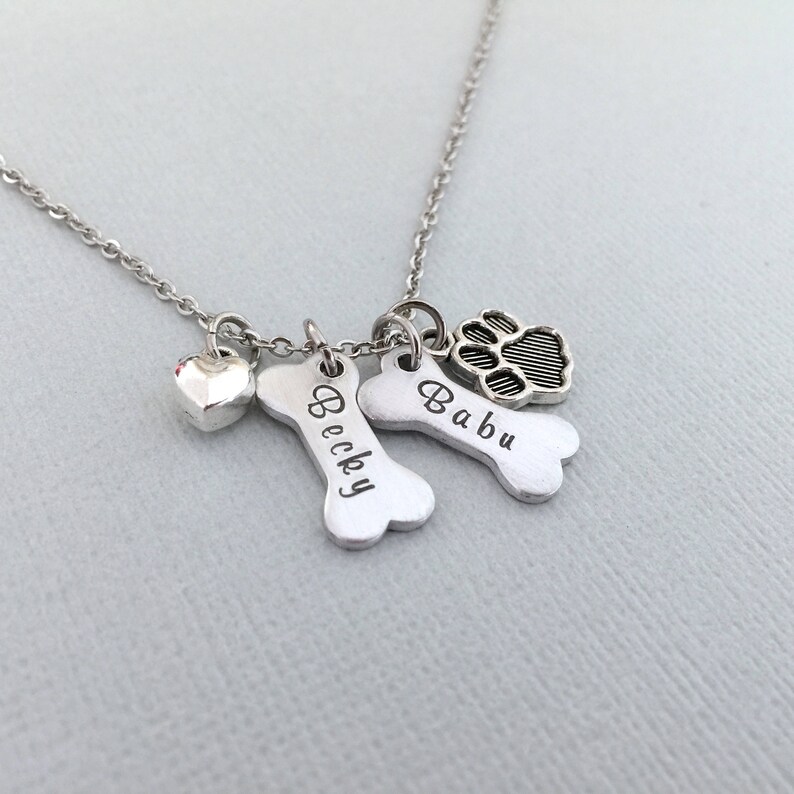 May include: Silver necklace with two bone charms engraved with the names "Becky" and "Babu" and a paw print charm.