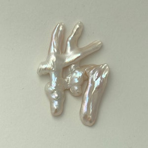 May include: A cluster of white baroque pearls with an iridescent sheen. The pearls are irregularly shaped and have a natural, organic look.