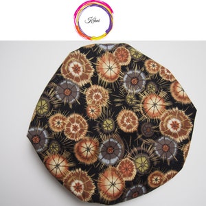 Puede incluir: Una tela negra con un patrón repetitivo de flores estilizadas marrones, naranjas y grises. Las flores tienen un diseño radiante con un círculo central.