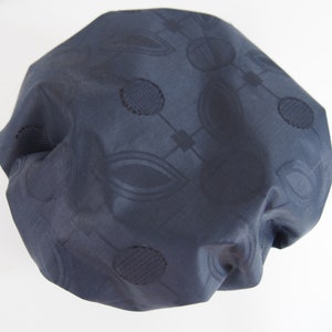 Puede incluir: Un gorro de ducha azul oscuro con un patrón geométrico. El patrón está formado por círculos y óvalos.