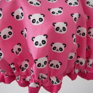 Puede incluir:  gorro de ducha rosa con un patrón repetido de caras de panda blancas y negras.