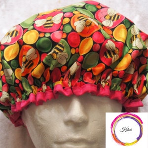 Puede incluir: Un gorro de ducha rosa y negro con un patrón colorido de abejas y círculos. El gorro está hecho de tela impermeable y tiene un borde rizado.