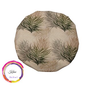 Puede incluir: Un gorro de ducha beige con un patrón de hojas de palma verdes y marrones. El texto "Kohni Deja 25 ans!!" está impreso en un círculo colorido.