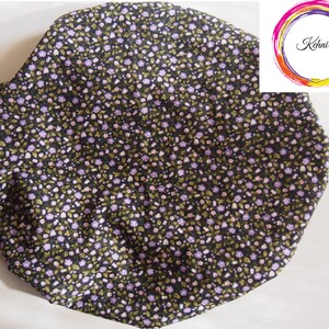 Puede incluir: Un gorro de ducha de tela negro con un pequeño estampado floral en tonos morados y verdes.
