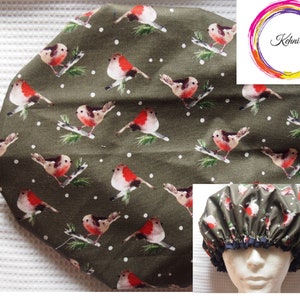 Puede incluir: Un gorro de ducha verde con un patrón de lunares blancos y un diseño repetido de petirrojos rojos en ramas. El gorro de ducha está hecho de una tela resistente al agua y tiene una banda elástica para un ajuste seguro.