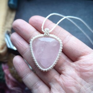 May include: A pink rose quartz pendant necklace with a white macrame cord.