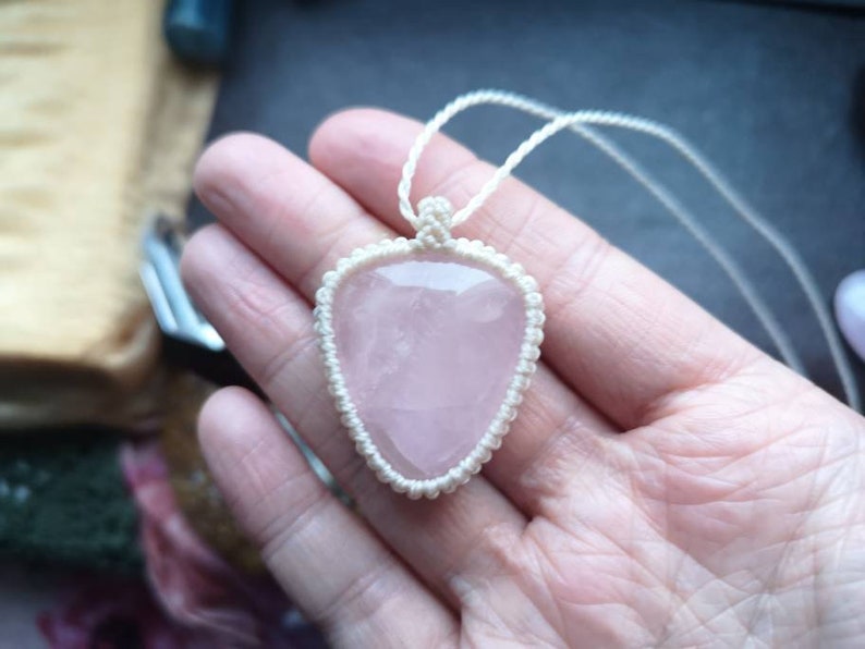 May include: A pink rose quartz pendant necklace with a white macrame cord.