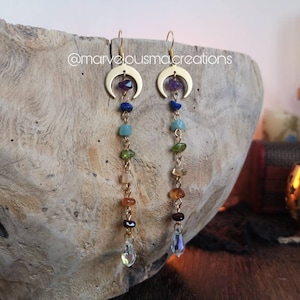 May include: Gold crescent moon earrings with a dangling chain of colorful gemstones and a crystal drop at the end.  @marvelousmac creations