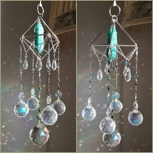 May include: A silver wire geometric crystal suncatcher with a teal gemstone hanging from the center. The suncatcher has multiple strands of crystals hanging from it, including clear teardrop crystals and smaller teal crystals.