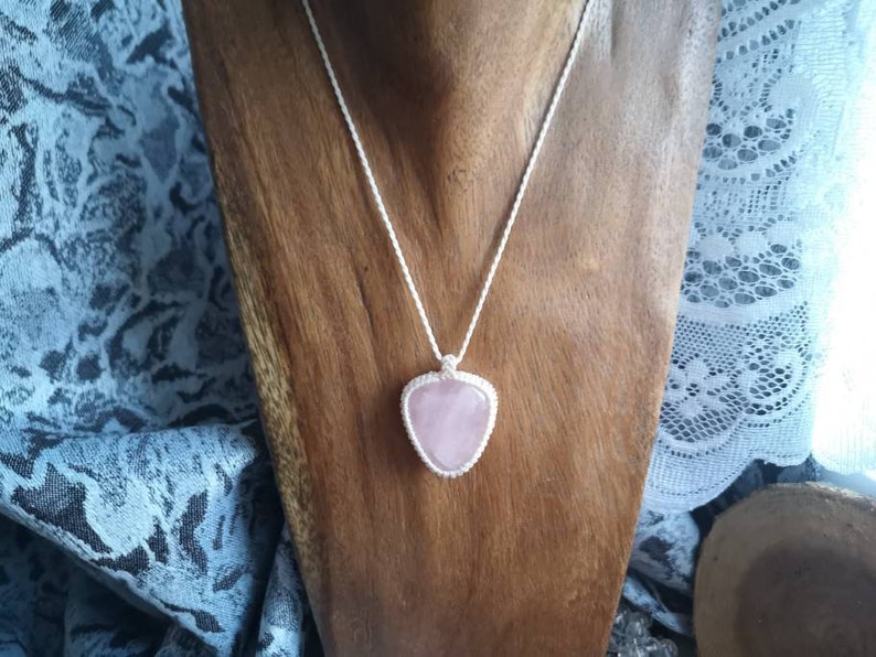 May include: A silver chain necklace with a pink heart-shaped pendant made of rose quartz.