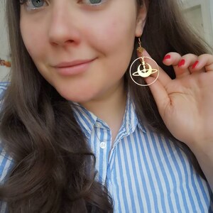 May include: Gold hoop earrings with a crescent moon, star, and ring design.