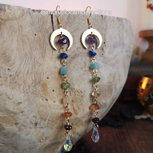 May include: Gold crescent moon earrings with a dangling chain of colorful gemstones, including amethyst, lapis lazuli, aventurine, peridot, citrine, carnelian, and garnet, ending with a clear crystal drop.