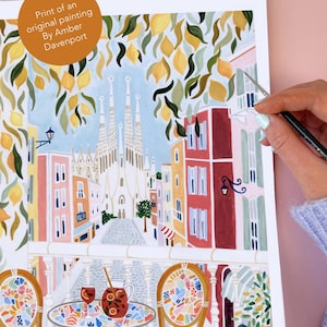 May include: Print of an original painting by Amber Davenport. The artwork depicts a vibrant street scene with colorful buildings, lemon tree branches, and a view of a cathedral. A table and chairs are in the foreground, with a pitcher and glasses of sangria.