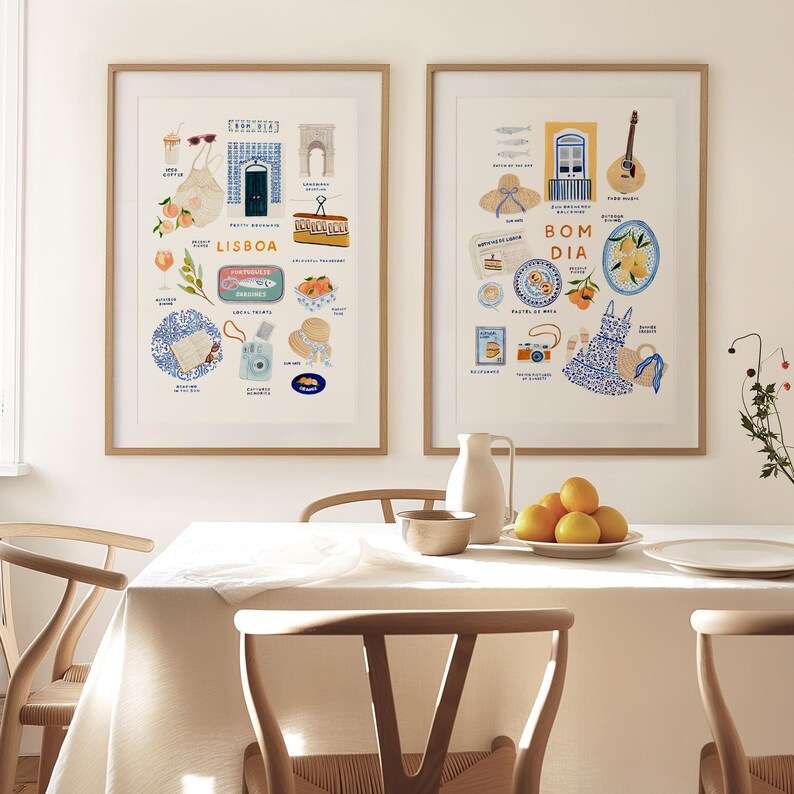 May include: Two framed art prints with illustrations of Lisbon and Portuguese culture. The Lisbon print includes a blue door, oranges, and the word "LISBOA." The other print says "BOM DIA" and features a guitar and a blue and white dress.