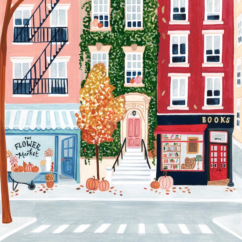 May include: An illustrated street scene depicting autumn, with a flower market, a bookstore, and residential buildings. The buildings are painted in pink, green, and red, with pumpkins and autumn leaves. The flower market has a blue awning and a cart of pumpkins.