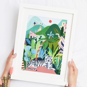May include: A white tiger with black stripes lies on a pink rock in a lush green jungle setting. The jungle is filled with palm trees, ferns, and other tropical plants. There are buildings in the distance, suggesting a city or town.
