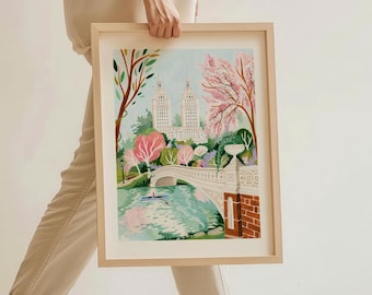May include: A framed illustration of a bridge over a lake in Central Park, New York City. The bridge is white with a stone railing and is surrounded by trees with pink flowers. Two tall buildings are visible in the background.