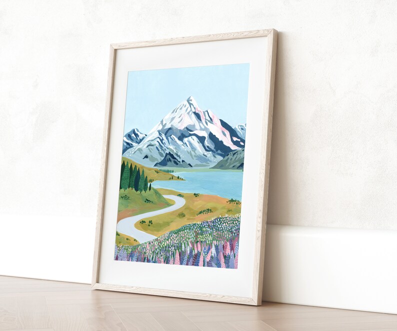 Puede incluir: Una ilustraci&oacute;n enmarcada de una cordillera con un lago y un camino sinuoso que conduce a un campo de flores moradas.