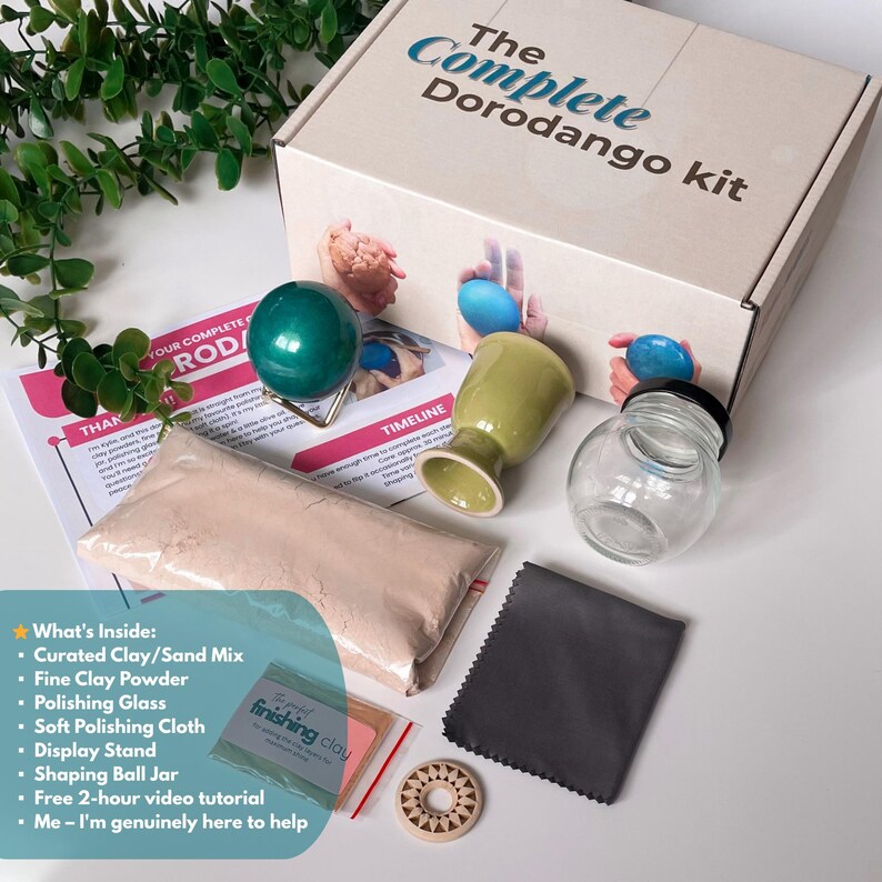 K&ouml;nnte beinhalten: Ein komplettes Dorodango-Kit in einer beigefarbenen Box mit dem Text "The Complete Dorodango kit". Es enth&auml;lt Ton, Polierglas, einen Pr&auml;sentationsst&auml;nder, ein Formkugelglas, ein weiches Poliertuch und ein kostenloses Video-Tutorial.