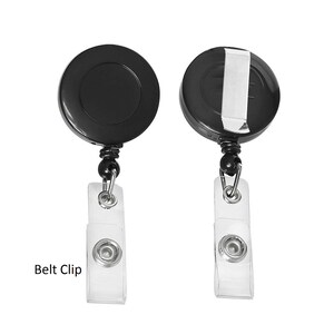 Puede incluir: Dos portatarjetas retr&aacute;ctiles negros con clips de tarjeta de pl&aacute;stico transparente. Uno muestra la parte posterior del soporte y el otro un clip de cintur&oacute;n de metal plateado. El texto "Belt Clip" es visible en la parte inferior izquierda.