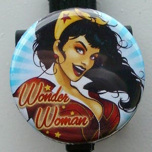 May include: A red, white, and blue Wonder Woman badge reel with a cartoon image of Wonder Woman. The text "Wonder Woman" is written in yellow with red stars.