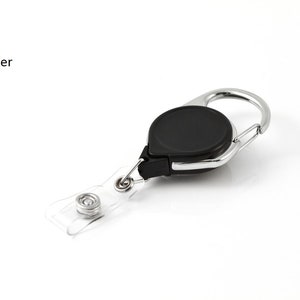 Puede incluir: Un mosquet&oacute;n negro y plateado con un cable retr&aacute;ctil y un porta-credenciales de pl&aacute;stico transparente. El mosquet&oacute;n tiene un dise&ntilde;o circular y el texto "Carabiner" es visible.