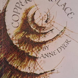 May include: Book cover titled "Copper Wire Lace" by Anne Dyer. The cover features an abstract design with copper-colored wire mesh and green and yellow accents against a white background. The title is in elegant script.