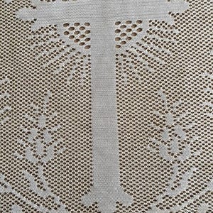 May include: White crocheted lace fabric with a cross design. The fabric has a delicate, intricate pattern and a scalloped edge.