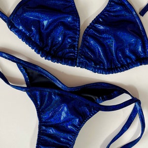 May include: A two-piece swimsuit in a vibrant blue with a shimmering, textured finish. The top is a classic triangle style, and the bottoms are a low-rise design. The swimsuit is made of a shiny material.