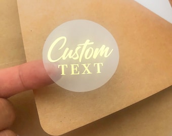 May include: A clear round sticker with gold lettering that says "Custom Text".