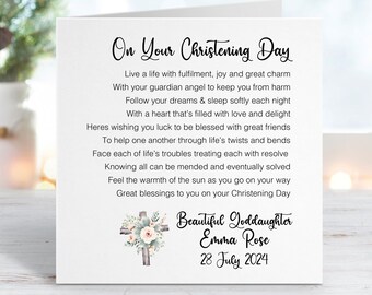 May include: A white card with a poem about a christening day. The poem reads "On Your Christening Day" and includes the text "Live a life with fulfillment, joy and great charm" and "Great blessings to you on your Christening Day". The card also includes a cross with flowers and the text "Beautiful Goddaughter Emma Rose 28 July 2024".