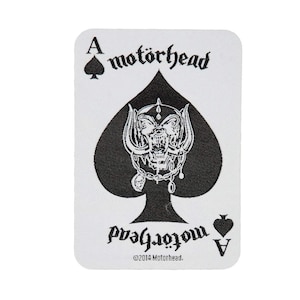 May include: A black and white playing card featuring the Ace of Spades. The card has a black spade with a white skull and crossbones design in the center. The text "motörhead" is printed in black at the top of the card and the text "A motörhead" is printed in black at the bottom of the card. The copyright symbol and the text "©2014 Motörhead." are printed in black at the bottom of the card.