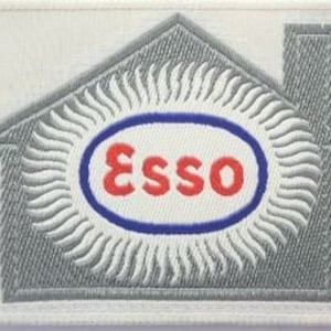 May include: A gray and white embroidered patch with a house shape, a sun with rays, and the word "Esso" in a red oval with a blue outline.