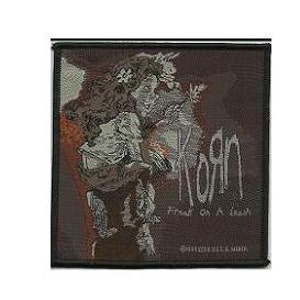 May include: A black and white embroidered patch with the band name "Korn" and the album title "Freak on a Leash". The patch features a dark, stylized image of a creature with horns.