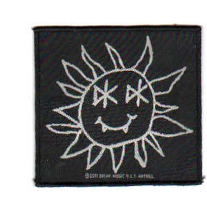 May include: Black and white embroidered patch with a smiling sun face with eyes that look like the letter "X". The text "1999 Decay Music B.V. & L.I. Antwill" is at the bottom of the patch.