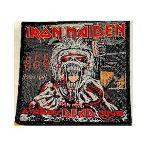 May include: Embroidered patch featuring the band name "Iron Maiden" in red letters above a detailed illustration of a monster with red eyes and a snarling mouth. The text "666 Radio Hell" and "A Real Dead One" are also included.