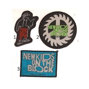 May include: Three New Kids on the Block patches. One is a black and white circular patch with a saw blade design and the words "New Kids on the Block" in green. Another is a black patch with a cartoon figure of a person wearing a hat and the words "New Kids on the Block" in red. The third is a blue patch with the words "New Kids on the Block" in silver.