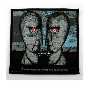 Peut inclure: Un patch tissé noir et blanc avec un graphique de deux visages aux yeux rouges. Le texte "©2001 PINK FLOYD MUSIC 1987 TO U.L.T. G.E.I. BY ANTHILL" est en bas du patch.