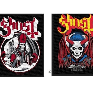 May include: Two black and white embroidered patches with the word "Ghost" in yellow and red lettering. The first patch features a skeleton wearing a red robe and a bishop's hat. The second patch features a red devil with horns and wings.