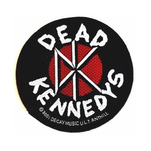 May include: Black and white embroidered patch with a red circle in the center. The circle has a white X shape inside. The text "DEAD KENNEDYS" is written around the circle. The text "©2001 DECAY MUSIC U.L.T. ANTHILL" is written below the circle.