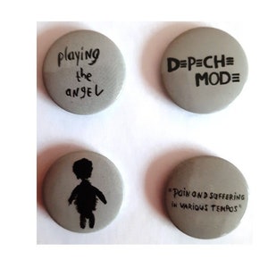 May include: Four grey round buttons with black text and images. The buttons feature the text "playing the angel", "D=P=CH=MOD=", "PAIN AND SUFFERING IN VARIOUS TEMPOS", and a silhouette of a person.