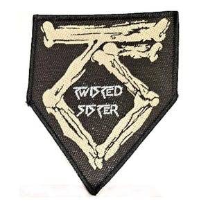 May include: Black and white patch with the words "Twisted Sister" in white, framed by a bone design. The patch is diamond-shaped and suitable for clothing or bags.