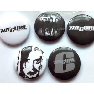 May include: Set of five black and white The Cure band badges. The badges feature the band's name, a band photo, and a stylised letter C.
