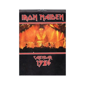 Może przedstawiać: Czarny i czerwony kalendarz z fotografią zespołu Iron Maiden występującego na scenie. Kalendarz jest na rok 1986.