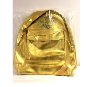 May include: A gold-colored backpack with a black "Bohemian Rhapsody" logo on the front.