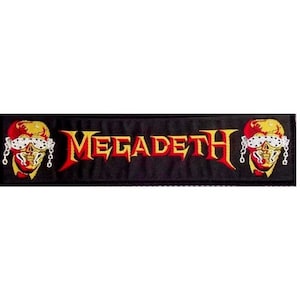 Peut inclure: Écusson brodé noir avec le nom du groupe "Megadeth" en lettres jaunes et rouges. Deux têtes de mort rouges et jaunes avec des chaînes sont de chaque côté du nom du groupe.